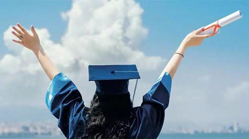 College graduate with hands upstretched to clouds.